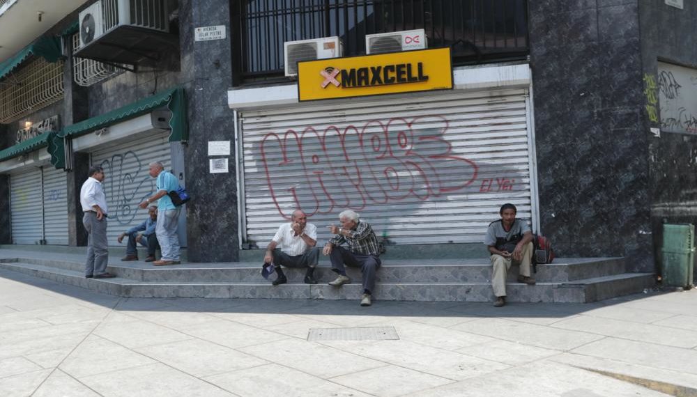 AME1310. CARACAS (VENEZUELA), 26/03/2019.- Varias personas conversan a las afueras de locales comerciales cerrados debido a un apagón este martes, en Caracas (Venezuela). Los cortes de luz aún persisten en algunas zonas de la capital venezolana. EFE/ Rayner Peña